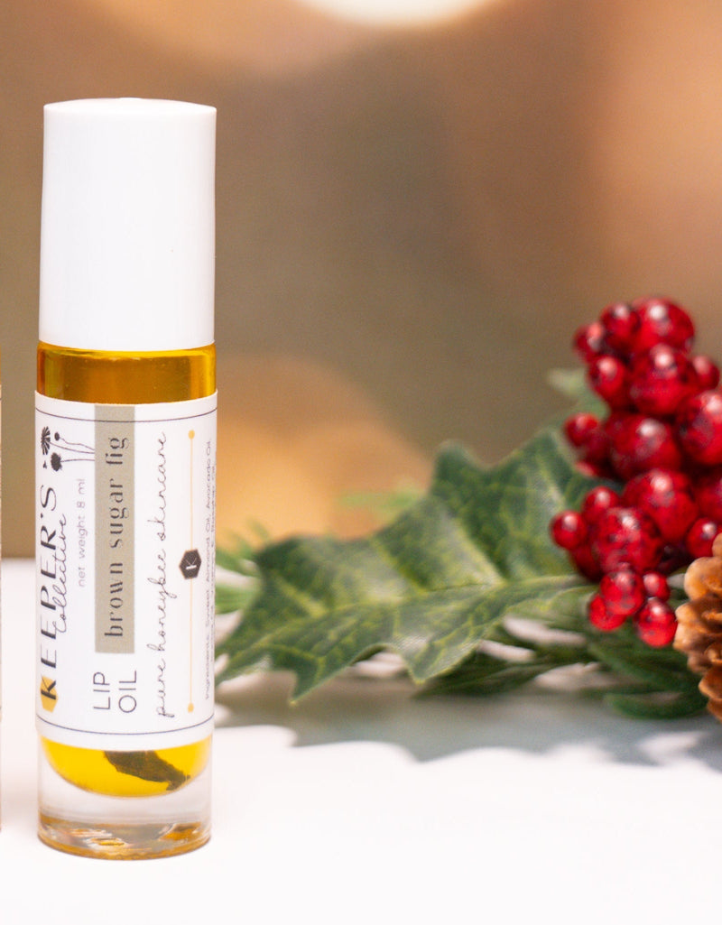 One small bottles with labels on a white surface with a festive background featuring berries and pine cones.